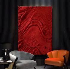 two chairs and a table in front of a wall with a red painting on it