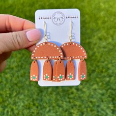 a pair of earrings is being held up in front of a green grass area with small white dots on it