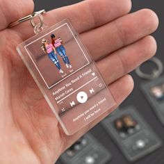 a hand holding a clear plastic keychain with an mp3 player on it