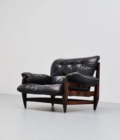 a black leather chair sitting on top of a white floor next to a wooden frame