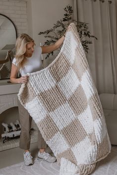 a woman holding up a blanket in front of a fireplace