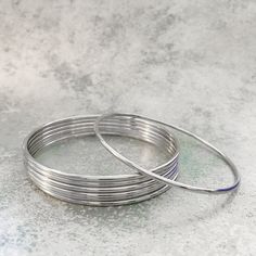 Our 2mm plain round stainless steel silver bangle bracelets are now available in multiple quantities and sizes! The medium size has an 8 inch inner circumference, the large size is 9 inches. Made from solid stainless steel, these durable stainless steel stacking bracelets will NEVER tarnish and are not susceptible to warping, scratches, dings or dents! Stainless is also a great alternative for people that have skin reactions with other types of metals. Your set will ship in a beautiful satin sto Life Necessities, Metal Bangles, Jewelry Bangles, Womens Silver Jewelry, Wishlist 2024, Ankle Jewelry, Stacking Bracelets, Stainless Steel Bangles, Stacked Jewelry