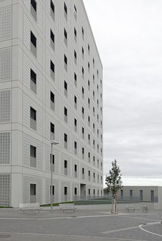 an empty parking lot in front of a large white building with many windows on it