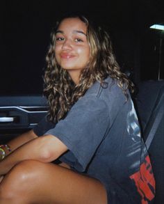 a woman sitting in the back seat of a car at night with her legs crossed