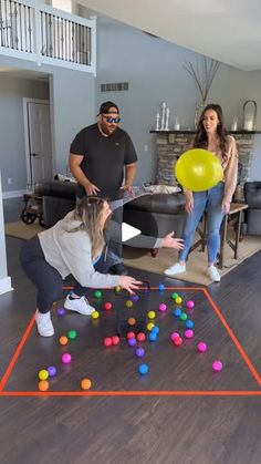 a group of people playing with balls on the floor in a living room while another person watches