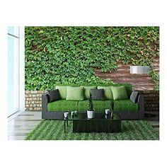 a green couch sitting in front of a lush green wall