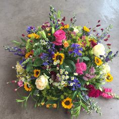 a bunch of flowers that are sitting on the ground in front of some concrete flooring