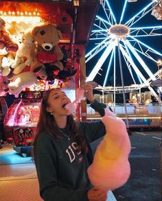 a woman eating cotton candy at an amusement park