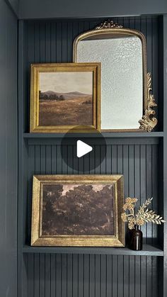 two framed pictures are hanging on the wall next to a shelf with paintings and vases