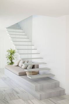 there is a white stair case in the living room with a plant on the floor