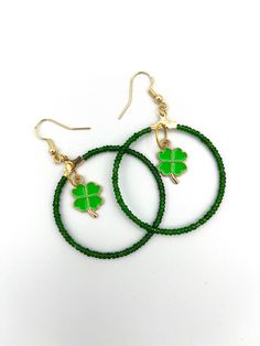 Emerald green seed bead hoop earrings. These earrings are 1-1/2 inch in diameter with a 2-1/2 inch drop length. Tiny metallic emerald green glass seed beads are strung on a sturdy stainless steel hoop wire. We added a 4 leaf clover charm to the center of the earrings symbolizing St. Patrick's Day or the celebration of new spring growth. The earrings hang from 18 karat gold plated 925 silver fish hooks. Pretty and shiny this fun pair of earrings are one of a kind and handmade with care. Green Beaded Hoop Earrings For Gift, Green Beaded Dangle Hoop Earrings, Green Hoop Earrings With Dangling Beads For Gift, Green Hoop Earrings With Ear Wire, Green Bohemian Hoop Earrings Hypoallergenic, Bohemian Green Hoop Earrings Hypoallergenic, Bohemian Green Hypoallergenic Hoop Earrings, Nickel Free Green Small Hoop Beaded Earrings, Nickel-free Small Hoop Green Beaded Earrings