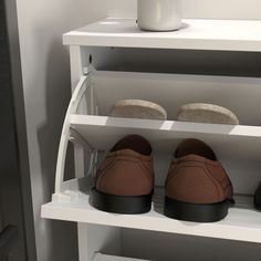 two pairs of shoes are sitting on a shelf in front of a coffee cup and mug