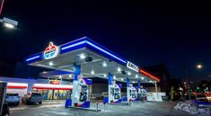 a gas station at night with cars parked in the lot