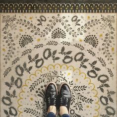 a person standing in front of a white and black tile floor with flowers on it