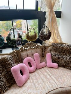 the word doll spelled out in pink letters on a leopard - print couch with matching pillows