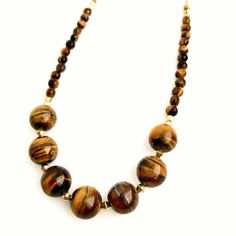 Very pretty golden Tiger's eye necklace. Large round Tiger's eye stone beads that measure about   inches with accent gold metal beads in between, & faceted Tiger's eye stone beads along the ends. This necklace measures about 23.75 inches in length & can be shortened if desired. (Please see the different length options for this necklace). Natural colors & swirl patterns in these stone beads. Shades of gold & brown, perfect for Fall! Tiger's Eye Crystal, Stone Beads Necklace, Golden Tiger, Tigers Eye Necklace, Color Swirl, Stone Beaded Necklace, Jewelry Accessories Ideas, Shades Of Gold, Accessories Ideas