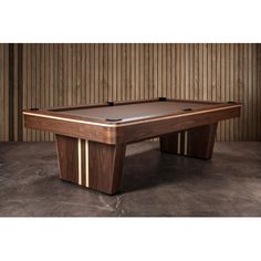 a pool table sitting on top of a cement floor next to a wooden paneled wall