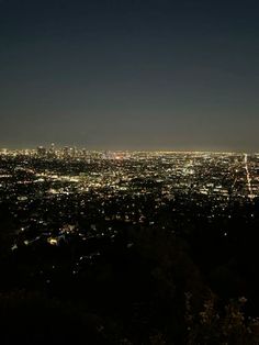 the city lights shine brightly at night from atop a hill in los angeles, california