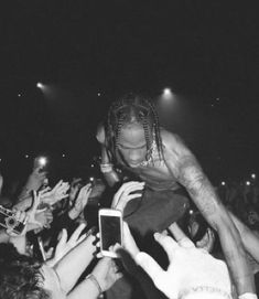 the man is holding up his cell phone in front of people at an outdoor concert