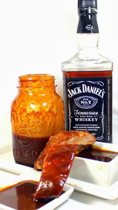 some food is sitting on a white plate and next to a bottle of jack daniels