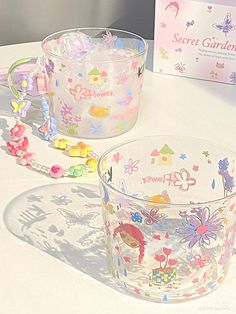 two clear glass cups sitting on top of a table next to a box and chain