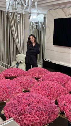 a woman standing next to a bunch of pink roses