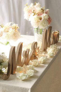 a table topped with flowers and wooden letters that spell out the word mr and mrs