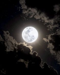 the full moon is shining brightly in the dark night sky with fluffy clouds and stars