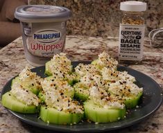 cucumbers with cream cheese and seasoning sitting on a plate next to an ice cream container