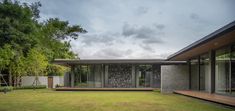 a modern house with large windows and grass in the front yard, on a cloudy day