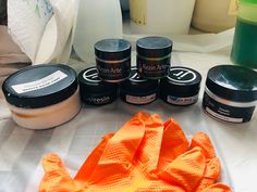 several different types of skin care products sitting on a white tablecloth next to an orange towel