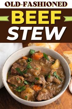 beef stew in a white bowl with bread on the side