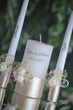 three wedding candles with ribbons and flowers on them