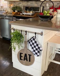 a kitchen island with an eat sign hanging from it's side and potted plants on the counter