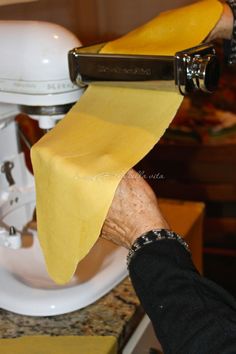 a person holding a piece of cheese over a paper towel in front of a blender