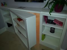 a white shelf with some books on it and a potted plant next to it