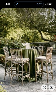 the table is set with four chairs and a green table cloth on top of it