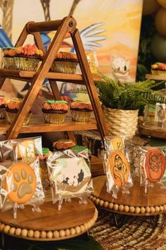 an assortment of cupcakes and treats displayed on wooden trays in front of a painting