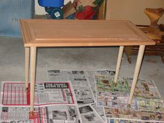 a wooden table sitting on top of a pile of newspapers