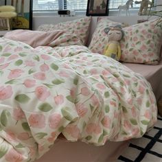 a bed with pink and green flowers on it in a bedroom next to a window