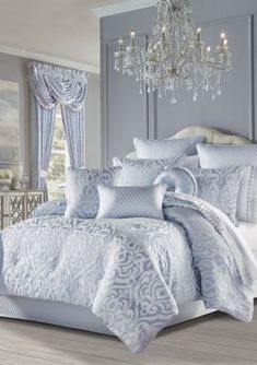 a bed with blue and white comforters in a bedroom next to a chandelier