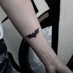 a person with a tattoo on their arm that has a batman symbol on the wrist