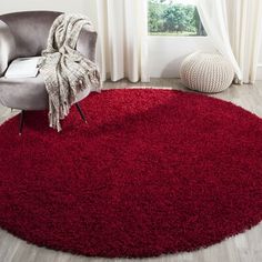 a red rug in a living room with a chair and large window behind the rug