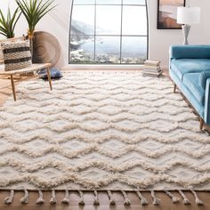 a living room filled with furniture and a white rug on top of a hard wood floor