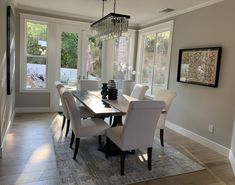 a dining room table with white chairs and a chandelier