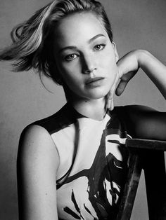 a black and white photo of a woman leaning on a chair