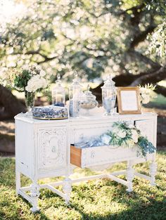 an old dresser is decorated with flowers and greenery for a wedding reception in the woods