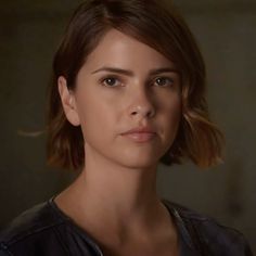 a close up of a person wearing a black shirt and looking at the camera with a serious look on her face