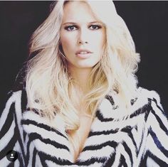 a woman with long blonde hair wearing a black and white striped coat looking at the camera