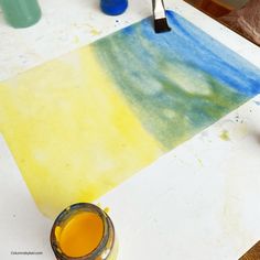 a paintbrush sitting on top of a table next to a yellow and blue painting